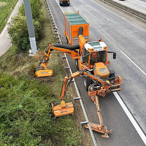 Pfanzelt K Trac mowing a motorway verge with mower booms in its mounting bays