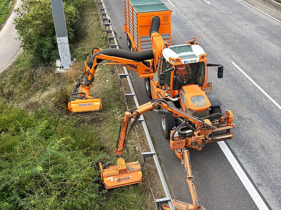 Pfanzelt K Trac mowing a motorway verge with mower booms in its mounting bays